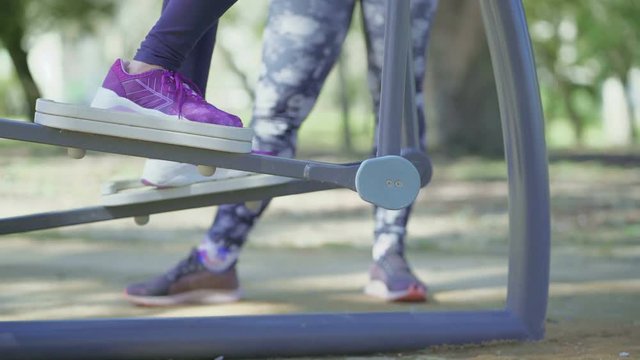 Cropped shot of woman training on orbitrek in park. Female trainer working with elderly client in park. Concept of sport