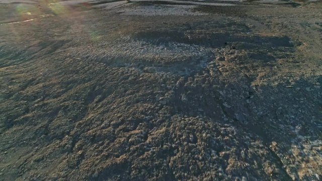 Fast, low aerial downward view, pulling away from dry, barren mudstone embankments in a desert