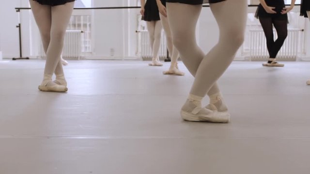 A group of young ballerina's training in a dance studio. Real time footage, close-up of their pointe shoes.