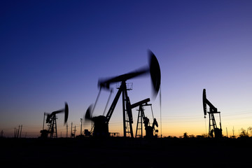 Oil pumps in action, silhouetted against the setting sun