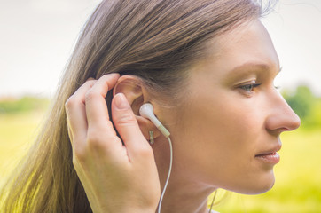 Young woman enjoying music in white headphones outdoors