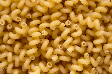 Top view of spiralli pasta. Yellow dry uncooked macaroni texture for background.