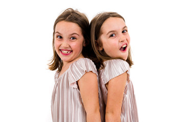 Identical twin girls are turned facing back to back.