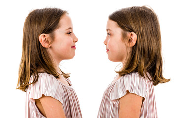 Identical twin girls are looking at each other and smiling.