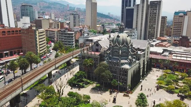 Still drone footage showing church and metro in Plaza Botero, bright sun in Medellin square