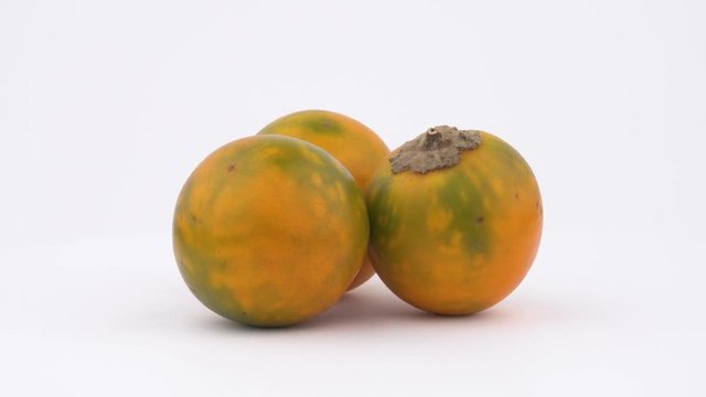 Three solanum quitoense, orange naranjilla fruits. Rotating on turn table. Isolated on the white background