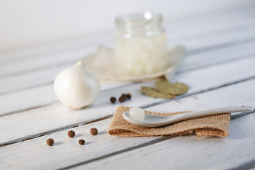 Glass Jar of Pickled Onions on White wood Background