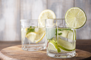 water with lemon and lime in glasses, detox concept on wooden background