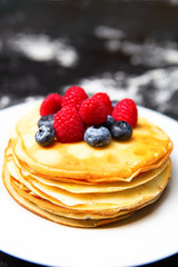 Photo of plate with pancakes, blueberries, raspberries.