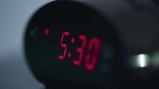 Close up shot of digital display on alarm clock flipping from 5:29 am to 5:30 am