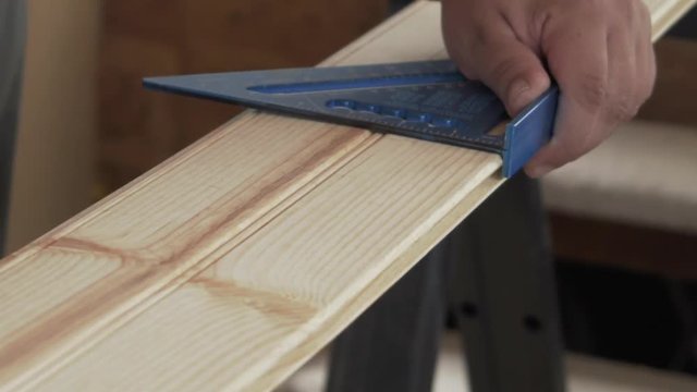 Man using speed square on plank of wood
