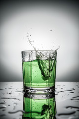 splash of lemonade in glass with drops on table on grey background