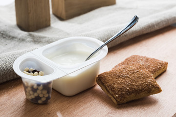 Yogurt with chocolate balls. Double plastic cup with white yogurt and sweet cinnamon cookies.