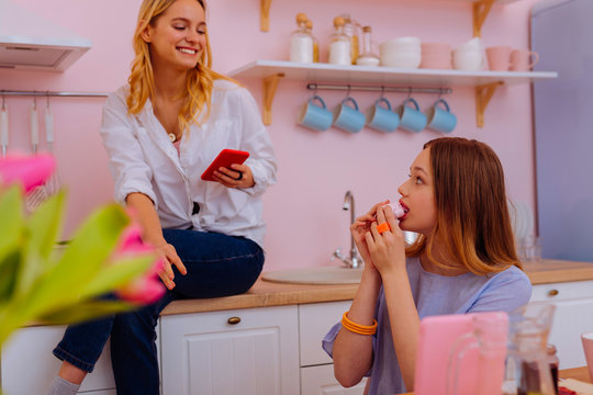 Teenage girl biting sweet zephyr having breakfast with sister