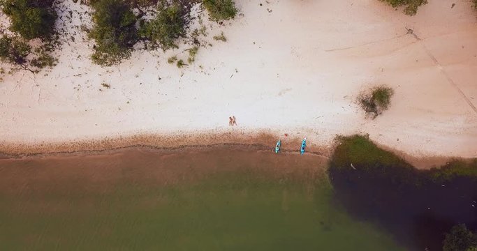 Couple rests at the beach after kayaking. Shot in the Amazon region in Brazil. No civilization anywhere near. Drone top view rising until almost un noticable.