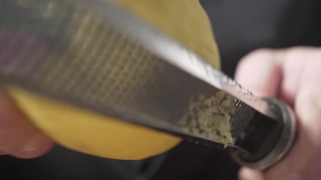 Handheld Close Up Restaurant Chef Zesting a Fresh Yellow Lemon.