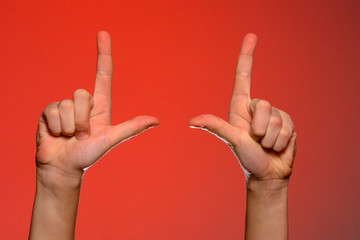 Human hand with folded fingers, shows an index finger that symbolizes a pistol, isolated on a red background