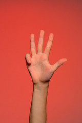 The human hand shows four fingers isolated on a red background
