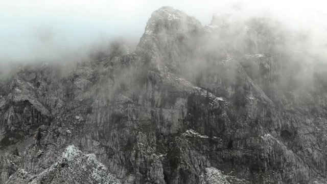 Aerial shot of a massive granite mountain covered in fog.