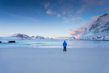 Fototapeta na wymiar A man stands on the ocean in winter in Norway in the Lofoten Islands