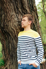 Fototapeta premium a man stands near a tree in a yellow striped jacket in nature 1