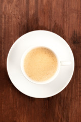 Coffee in a simple white cup, shot from the top on a dark rustic wooden background with a place for text