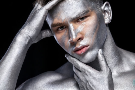 A fashion portrait of man with silver bodyart and face art.