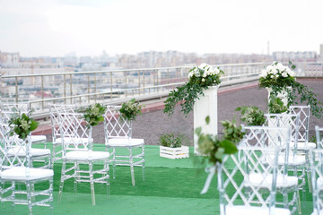 wedding arch withwhite chairs and white flowers on green grass outdoor