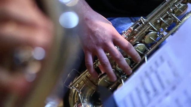Close-up rack focus from one band member to another as they play saxophone