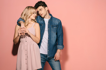 girlfriend in pink dress and handsome boyfriend in denim shirt hugging and looking at each other