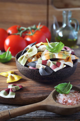 Ingredients of Italian cuisine: raw farfalle pasta, bunch of ripe tomatoes, basil and olive oil