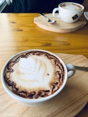 cup of coffee with cream on wooden background