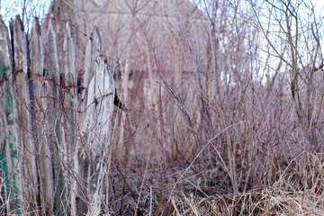 Old abandoned house behind a broken wooden fence