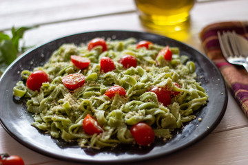 Green pasta with tomatoes and parmesan cheese. White background.