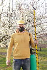 Portrait of the agricultural worker with spraying equipment. Disease and insect management in the fruit orchard. Fruit tree care.
