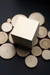 Pine tree cross-sections with annual rings and wooden cube on black surface. Lumber piece close-up.