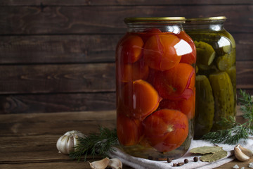 pickled tomatoes and cucumbers in a glass jar on a wooden table