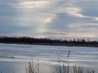 River in the early spring morning. The sun's rays pass through the clouds and illuminate the river. Ice descends from the river.