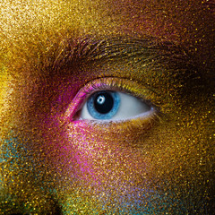beautiful female eye with yellow, purple, blue and green paint on the skin, space and stars. Creative makeup close-up. macro.