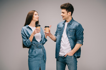 girlfriend in denim dress and smiling boyfriend in jeans and shirt holding paper cups and talking