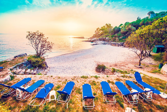 Fabulous beautiful magic dawn on Bataria Beach with sun beds for sunbathing on the coast of the Ionian Sea in Corfu (Керкіра), Greece. Amazing places. Tourist Attractions.