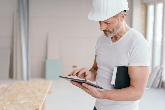 Serious builder checking something on a tablet