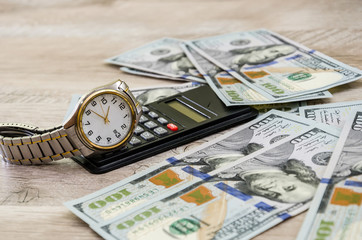 wrist watch on dollars and calculator