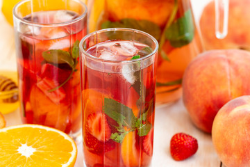 Healthy berry fruit cocktails. Summer refreshing drinks, fruit and berry raspberry mojito or lemonade with fresh mint, peach, strawberry, slices of orange, lemon and honey on a light background.