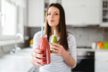 Focus on red smoothie in teenage girl hand. Girl offering healthy drink.