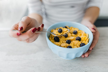 Close up of corn flakes with blueberry in blue ceramic bowl