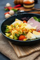 Salad with speck ham and egg, tomatoes