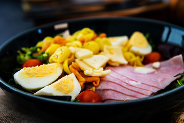 Salad with speck ham and egg, tomatoes