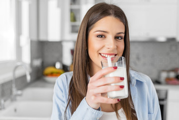 Close up of happy young woman drinking milk.