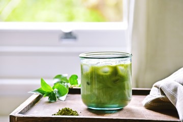 Glass of iced matcha green tea latte on the light home background 